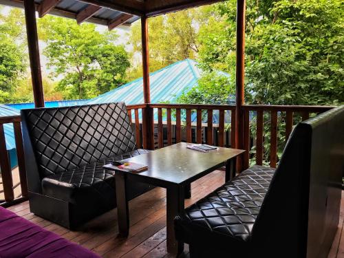 a porch with two chairs and a table on a deck at Park Hostel Osh in Osh