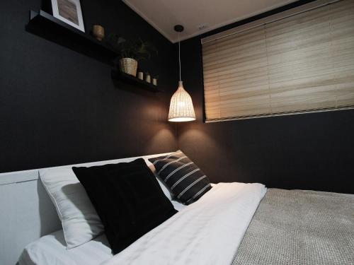 a bedroom with a bed with black walls and a lamp at Neat House in Seoul