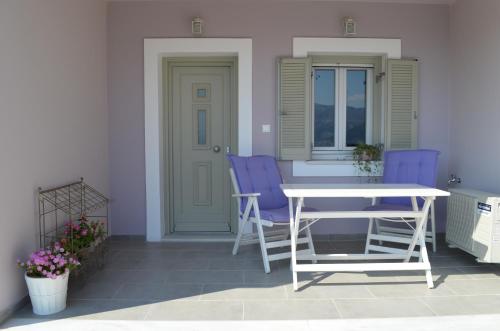 un patio con sillas moradas y una mesa blanca en Romanza Studios, en Asos
