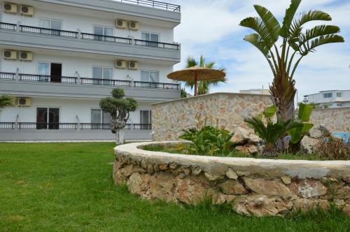 a building with a palm tree and a stone wall at Kostas Studios in Faliraki