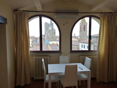 mesa y sillas en una habitación con 2 ventanas en La Casa del Gigli, en Monte San Savino
