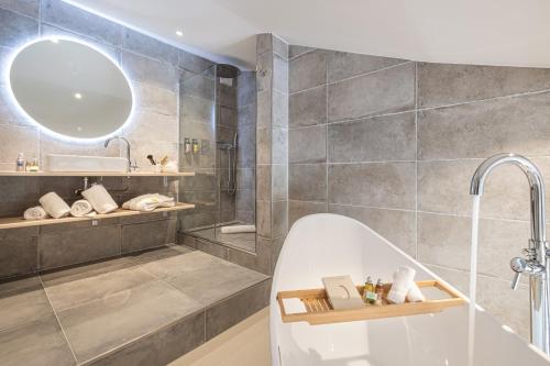 a bathroom with a tub and a sink and a mirror at Hotel & Spa des Gorges du Verdon in La Palud sur Verdon