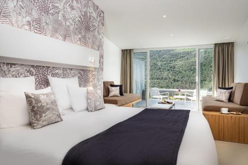 a bedroom with a large bed with a large window at Hotel & Spa des Gorges du Verdon in La Palud sur Verdon