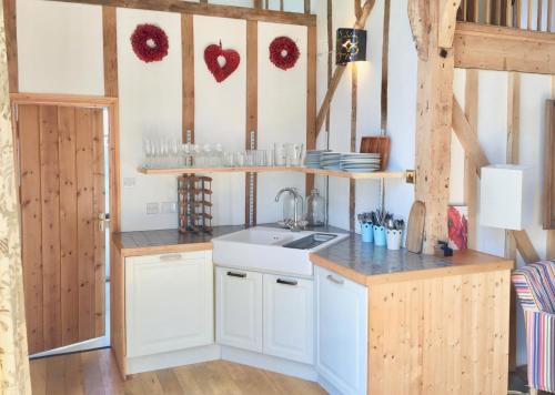 a kitchen with white cabinets and a sink and shelves at Partridge Lodge Self Catering houses in Woodbridge