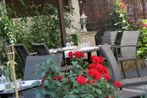 a table and chairs with red flowers on a patio at Logis Hôtels Restaurant Les 3 Rois in Issoudun