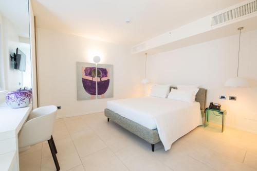 a white bedroom with a white bed and a chair at Le Funi Hotel in Bergamo