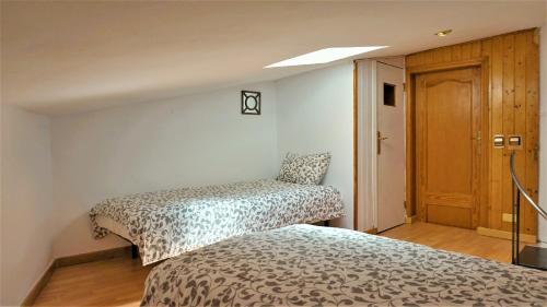 two beds in a small room with a door at Casa Borguny - House in the centre of Palma in Palma de Mallorca