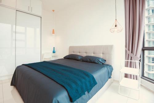 una camera da letto con un letto con una coperta blu e una finestra di Robertson Suites Kuala Lumpur a Kuala Lumpur
