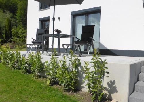 eine Terrasse mit Stühlen und einem Sonnenschirm auf einem Haus in der Unterkunft Ferienwohnung Selina-Sophie in Sehringen