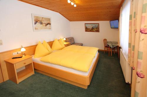 1 dormitorio con 1 cama con sábanas amarillas y silla en Ferienwohnung/Apartment Erna Prommegger, en Grossarl