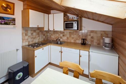 a kitchen with white cabinets and a sink and a microwave at Haus Barbara in Nauders