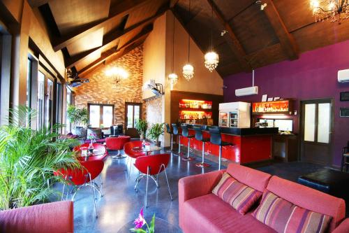 a restaurant with red furniture and a bar at Laluna Hotel And Resort, Chiang Rai in Chiang Rai