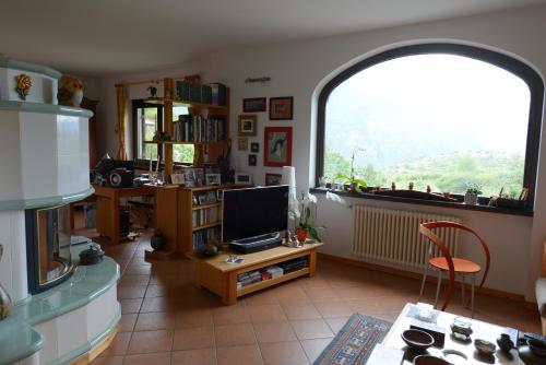 a living room with a large window and a television at B&B Scotty & Co. in Susa