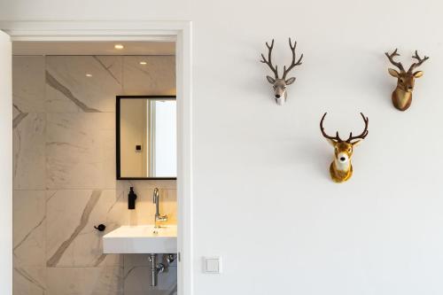 baño con lavabo y cabezas de ciervo en la pared en Paulus Loot Zandvoort, en Zandvoort