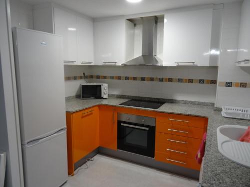 サン・カルラス・デ・ラ・ラーピタにあるApartamento Piso Rapita 19のキッチン(オレンジ色のキャビネット、コンロ付)