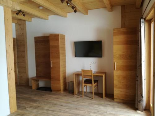 Habitación con mesa y TV en la pared. en Wieser Hütte, en Stockenboi