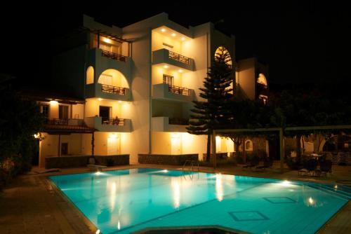 a swimming pool in front of a building at night at Sarikampos Beach in Myrtos