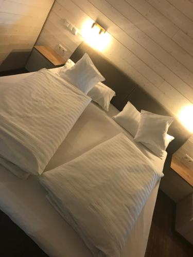 a large bed with white sheets and pillows on it at Ferienwohnung Zum alten Rathaus in Schleiden