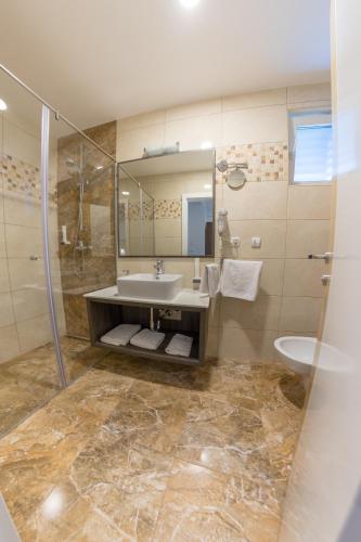 a bathroom with a sink and a shower and a toilet at Hotel Rekic in Bihać