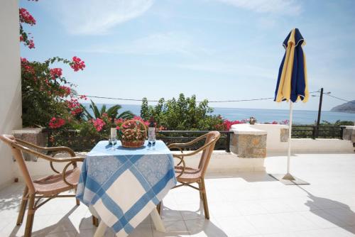 a table and chairs with an umbrella and the ocean at Sarikampos Beach in Myrtos