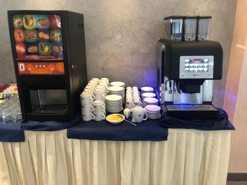 een tafel met een koffiezetmachine, kopjes en borden bij Hotel Marzia con Piscina in Riccione