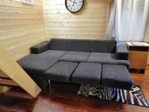 a couch in a room with a clock on the wall at Ainja Puhkemaja in Viljandi