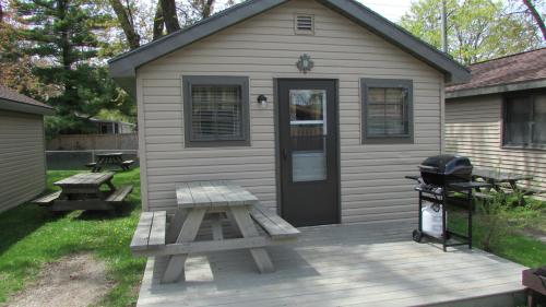 a house with a picnic table and a grill on a deck at The Maples Cottages in Port Elgin in Port Elgin