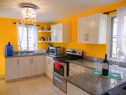 eine Küche mit gelben Wänden und weißen Schränken in der Unterkunft Playa Dorada Mountainview Villa in San Felipe de Puerto Plata