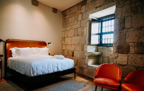 a bedroom with a bed and a red chair at Exmo Hotel by Olivia in Porto