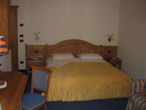 a bedroom with a bed and a desk and a chair at Hotel Lido - slow & natural living in Molveno