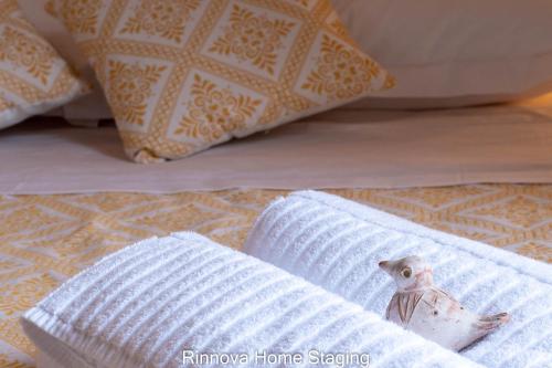 a bird figurine sitting on a towel on a bed with pillows at Villa Vitto - Sleep & Go in Capoterra