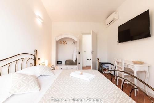 a white bedroom with a bed and a flat screen tv at Villa Vitto - Sleep & Go in Capoterra