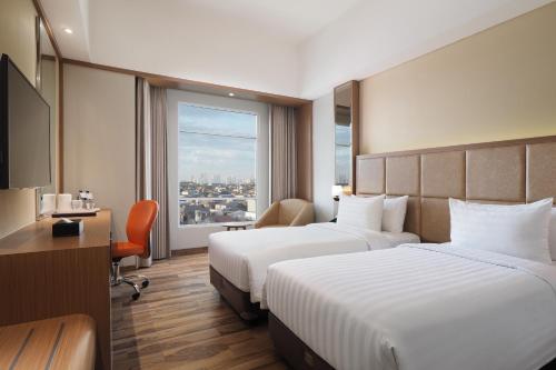 ein Hotelzimmer mit 2 Betten und einem Fenster in der Unterkunft Horison Ciledug Jakarta in Jakarta