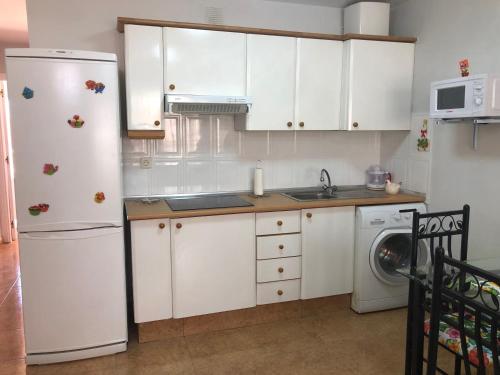 uma cozinha com armários brancos e um frigorífico branco em Paulalucía em Costa de Antigua