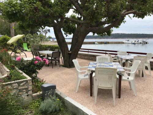 a group of tables and chairs next to the water at Apartment One in Rab