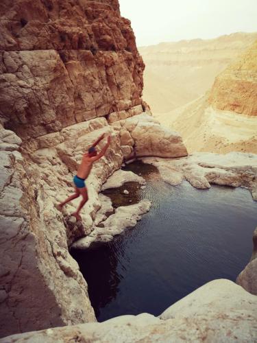 a man jumping into a body of water in a canyon at Dead Sea Desert's Edge in Arad