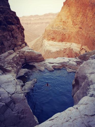 a person in a pool of water in a canyon at Dead Sea Desert's Edge in Arad