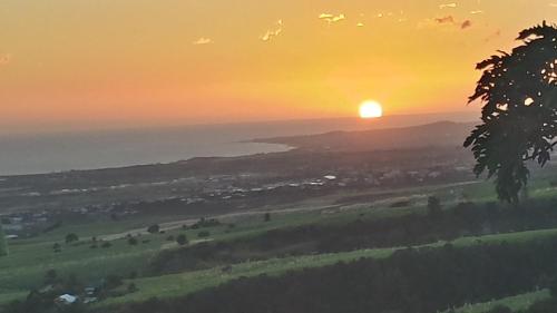a sunset over a field with the sun in the sky at Hôtel Le Soleil Couchant in Saint-Pierre