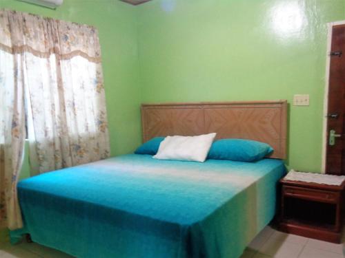 una camera da letto con un letto con lenzuola blu e una finestra di Yard Style a Kingston