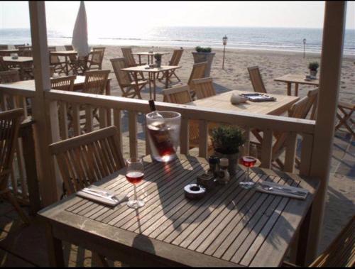 a wooden table with glasses of wine on the beach at Casa Blanca Zandvoort in Zandvoort