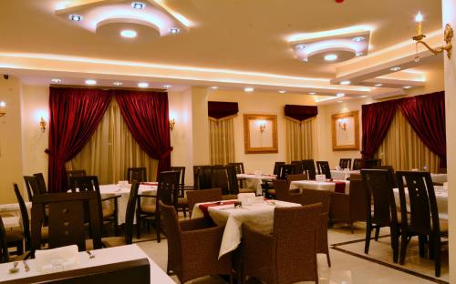 a restaurant with tables and chairs and red curtains at Bissau Royal Hotel in Bissau