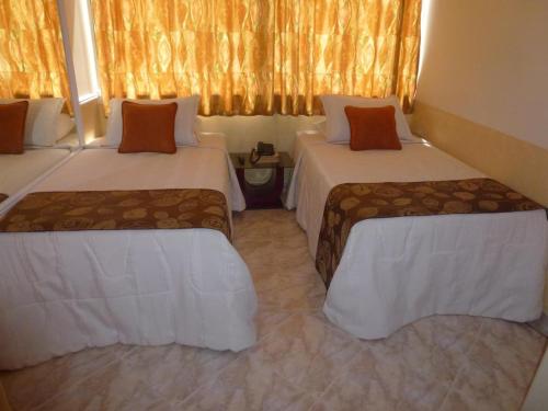 a hotel room with two beds with orange curtains at Hotel San Nicolas in Bucaramanga