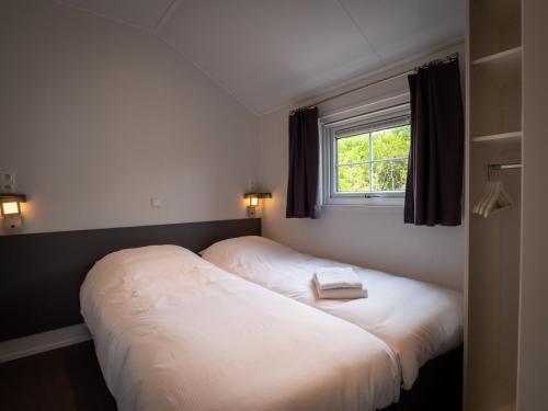 a bedroom with a large white bed with a window at Luxe Lodge Zeehoeve in Harlingen