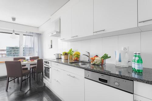 a white kitchen with a counter and a table at Swiss Star Zurich Oerlikon - Self Check-In in Zurich