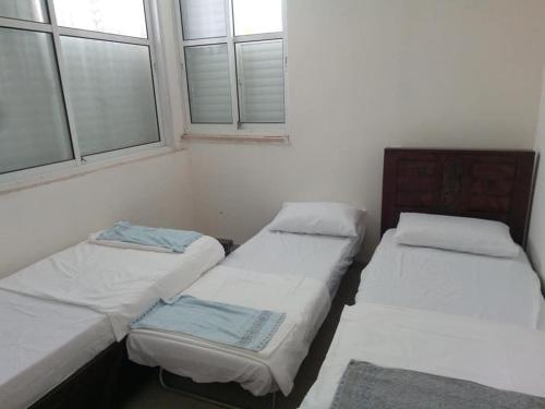 two twin beds in a room with two windows at Sheffer in Ramat Gan