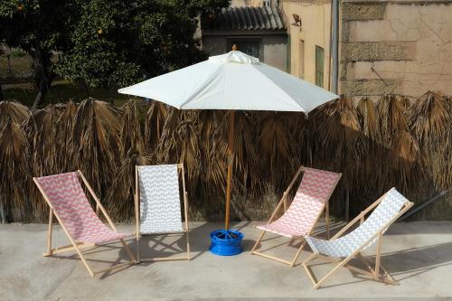 three chairs and an umbrella on a patio at La Casina de Micaela in Perales del Puerto
