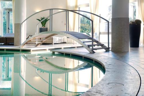 a swimming pool with a bridge in a building at Villasanpaolo Resort & Spa in San Gimignano