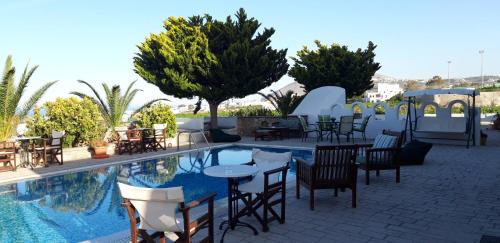 a patio area with tables, chairs, and a pool at Villa Koronios in Fira