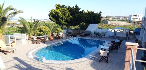 a beach with a pool, chairs, and a pool table at Villa Koronios in Fira