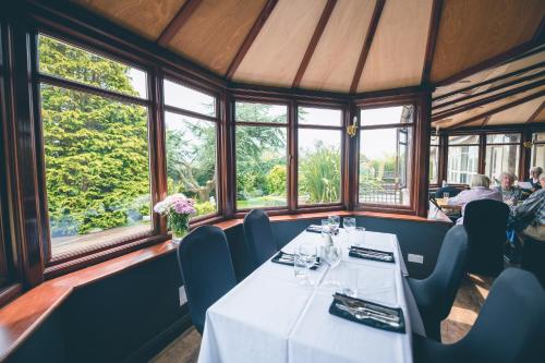 a dining room with tables and chairs and windows at The Grange Hotel Brent Knoll in Highbridge
